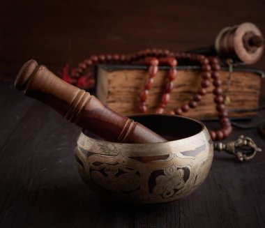 Kahverengi ahşap masa üzerinde ahşap bir çırpıcıyla Tibet 'te şarkı söyleyen bakır kâse meditasyon ve alternatif tıp aletleri.