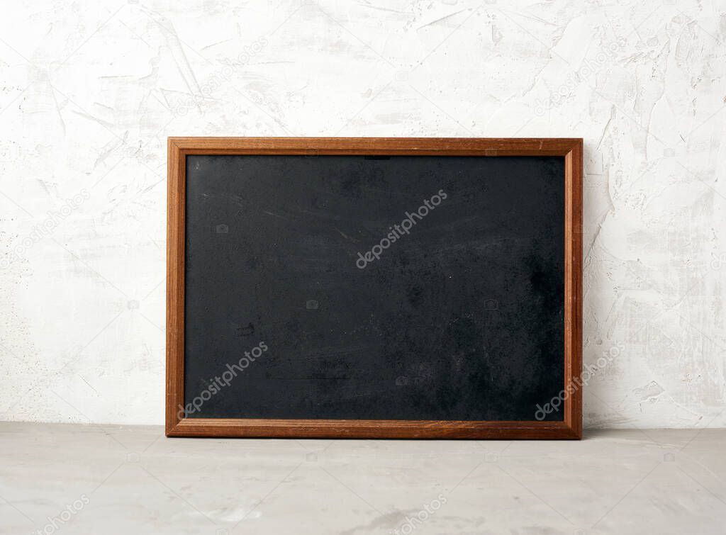 empty wooden rectangular frame, chalk board for writing a to-do list, menu on a white cement background. Back to school