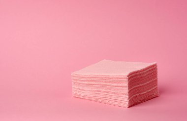 Pembe arka planda tek kullanımlık pembe kare peçete yığını. Yazı için bir yer.