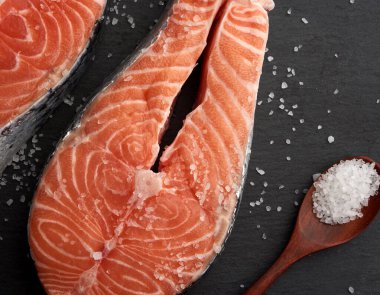 Siyah arka planda beyaz tuzlu çiğ somon bifteği.