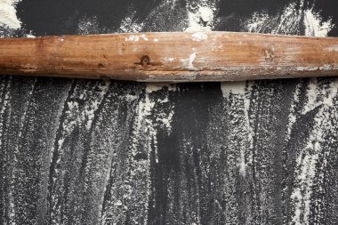 Siyah bir masaya saçılmış beyaz buğday unu ve siyah bir masanın üzerindeki eski kahverengi ahşap raptiye.