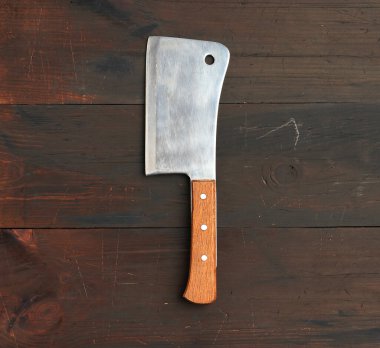Kahverengi ahşap arka planda et ve sebze kesmek için büyük bir mutfak bıçağı.