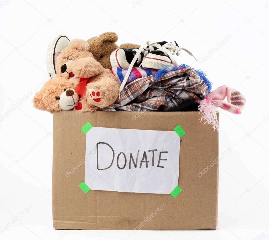 brown cardboard box with a white sheet pasted and the inscription donate on a white background, inside clothes, toys, help concept