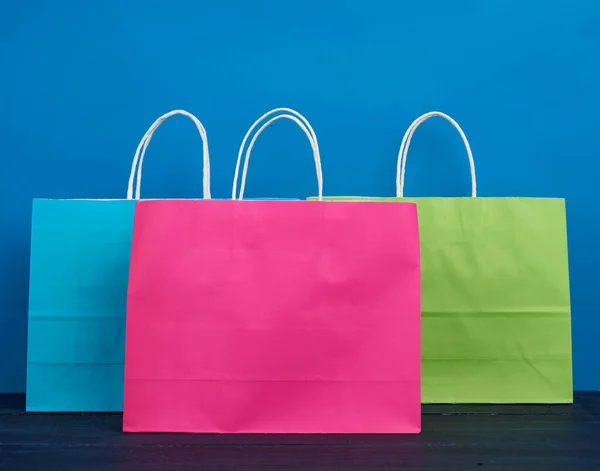 青い背景にショッピングやギフト用のハンドルを持つ多色の紙袋 — ストック写真