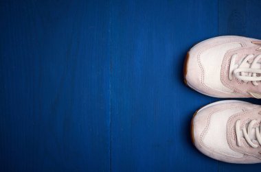 Mavi ahşap arka planda bir çift deri pembe spor ayakkabı, üst manzara, boşluğu kopyala