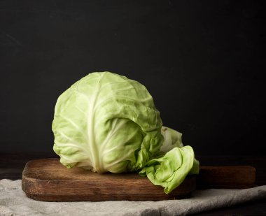 Kahverengi ahşap bir tahtanın üzerinde taze yeşil lahana, sağlıklı yiyecekler.