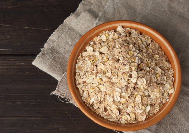 Tahta bir masada, kahverengi seramik tabakta çiğ yulaf ezmesi.