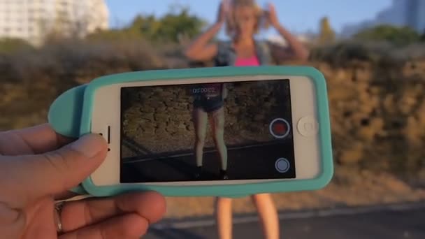 Schönes Mädchen, das am Strand tanzt, ihr Freund schießt das am Telefon — Stockvideo