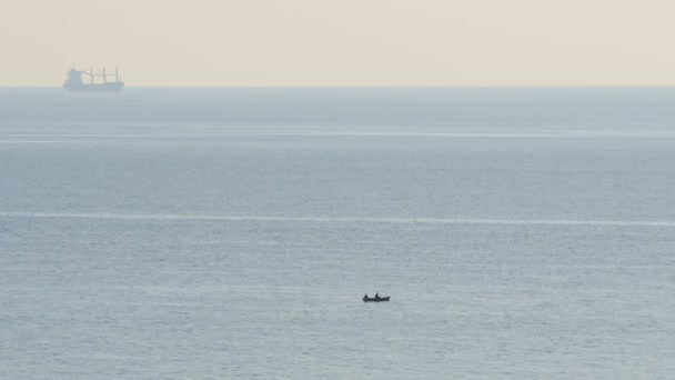 Am frühen Morgen Sonnenaufgang über dem Meer, wo Fischer im Boot und große Boot weit weg — Stockvideo