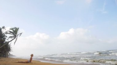 İnce bir rakam olan kadın dalgalar yakınındaki jimnastik yoga yapan