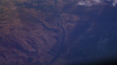 Mountain view mavi gökyüzünde bulutlar yukarıda bir uçak penceresinden