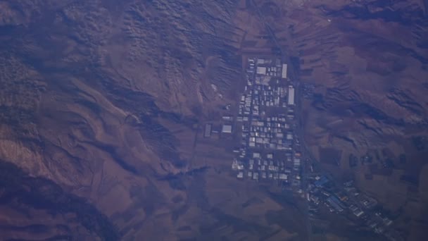 Kijk door het raam van een vliegtuig boven de bergen in de blauwe lucht in de wolken — Stockvideo