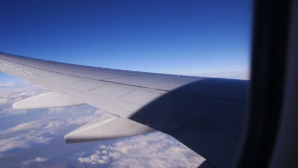 Вид через окно самолета в голубом небе в облаках — стоковое видео