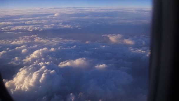 Mountain view from an airplane window above the earth in the blue sky in clouds — Stockvideo