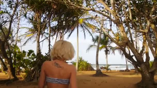 Mira atrás de la chica caminando en la playa del océano Índico lentamente — Vídeos de Stock