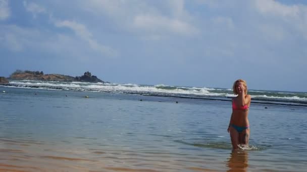Дівчина, посміхаючись і насолодитися моментом Шрі Lankas пляж виходити від Індійського океану — стокове відео