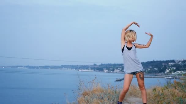 Красивая блондинка танцует на пляже на рассвете и птицы на заднем плане — стоковое видео