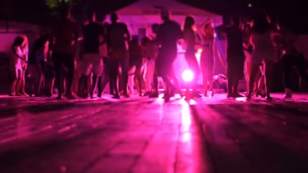 Bunte Lichter wirbeln und drehen im Nachtclub, wenn die Menschen verschwimmen — Stockvideo