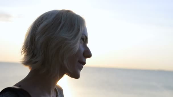 Belle fille blonde marche en harmonie souriante près de la plage au lever du soleil — Video