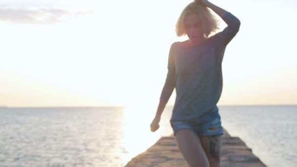 Hermosa chica camina sonriente y feliz cerca de la playa al amanecer — Vídeos de Stock