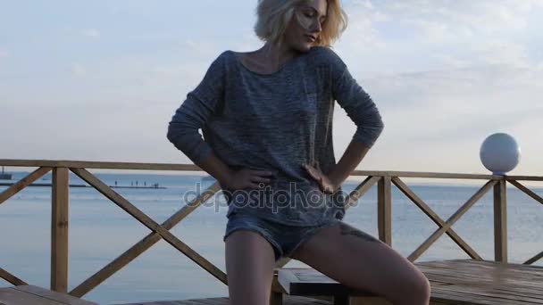 Blond girl dancing happy near the beach on the wooden bridge at sunrise — Stock Video