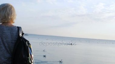 Uzun bacaklı kızla renkli çantasını martı ile plaja yakın ile yürüyor