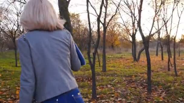 Jeune femme bonheur dansant parmi les feuilles colorées d'automne au coucher du soleil 