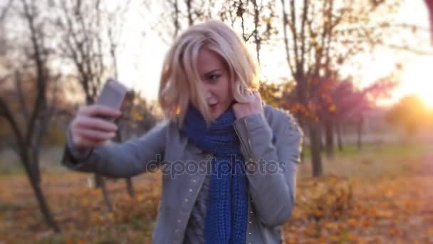Mladá žena štěstí selfie mezi podzimní barevné listí v západu slunce — Stock video