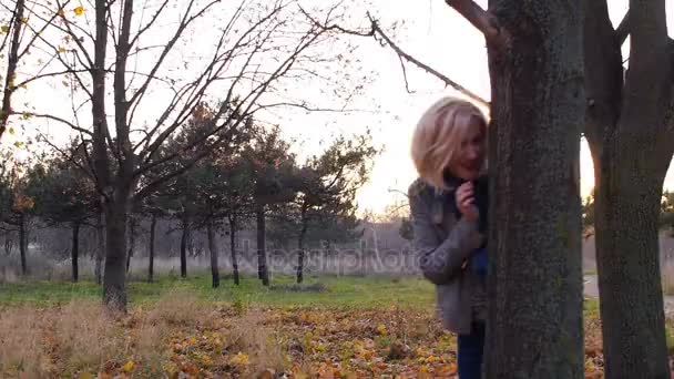 Jeune femme bonheur caché parmi les feuilles colorées d'automne au coucher du soleil — Video