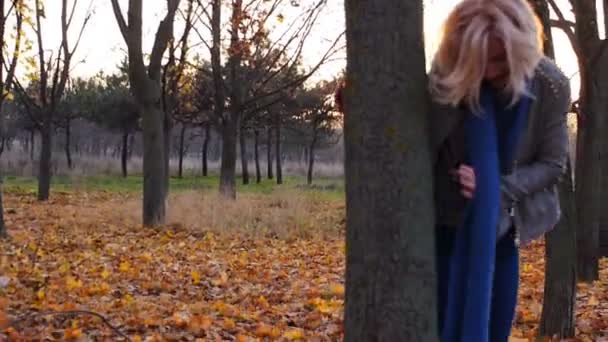 Jeune femme bonheur caché parmi les feuilles colorées d'automne au coucher du soleil — Video