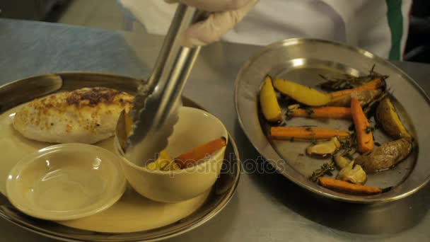 Close-up van chef-kok handen krijgen aardappel met wortels als garnering — Stockvideo