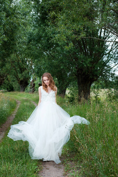 Portrait of young pretty woman (bride) in white wedding dress outdoors, make up and hairstyle
