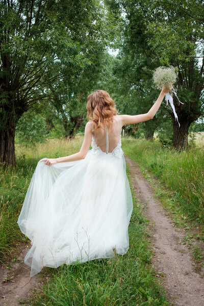 Portrait of young pretty woman (bride) in white wedding dress outdoors, hairstyle