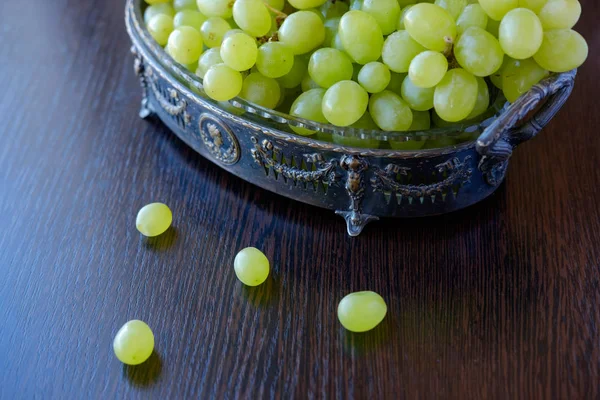 Haufen grüner Trauben in Retro-Vase auf hölzerner Oberfläche bei Tageslicht — Stockfoto