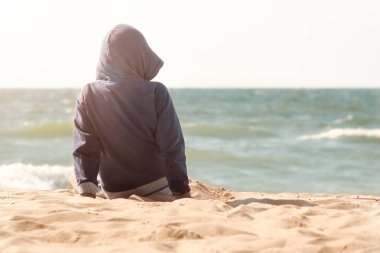 küçük çocuk (çocuk) oturma backfront Baltık Denizi sahil üzerinde