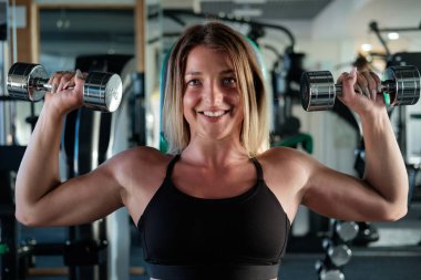 atletik kızı spor salonunda dumbbells ile egzersiz yaparak 