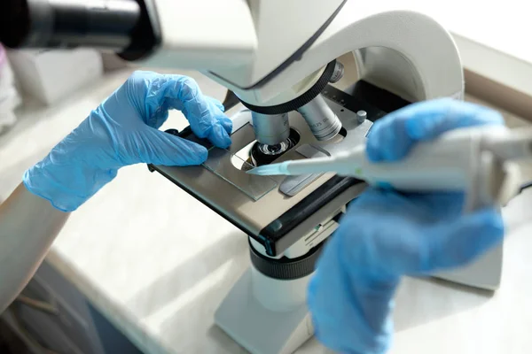 Mujer trabajadora trabajando con microscopio sosteniendo pipeta automática — Foto de Stock