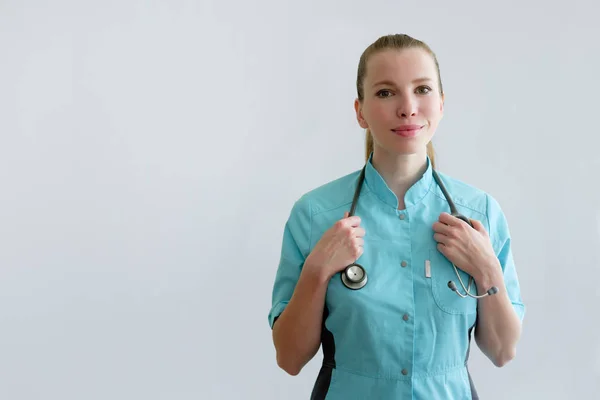 Mujer joven médico con estetoscopio aislado en gris —  Fotos de Stock