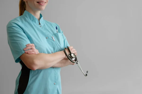 Mujer joven médico con estetoscopio aislado en gris —  Fotos de Stock