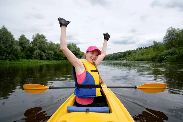 Giovane ragazza in berretto rosa canottaggio in kayak sopra il fiume, avendo fu — Foto Stock