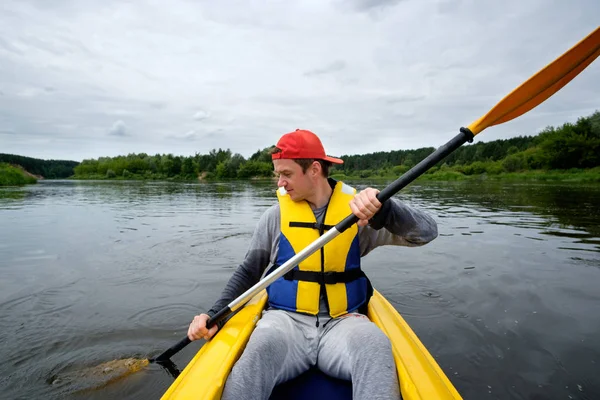 Homme en bonnet rouge ramant en kayak sur la rivière — Photo