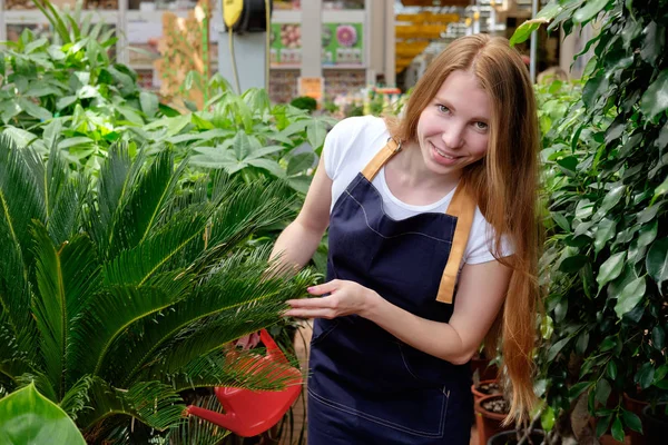 Рыжая молодая женщина, работающая в теплице на рынке растений. — стоковое фото