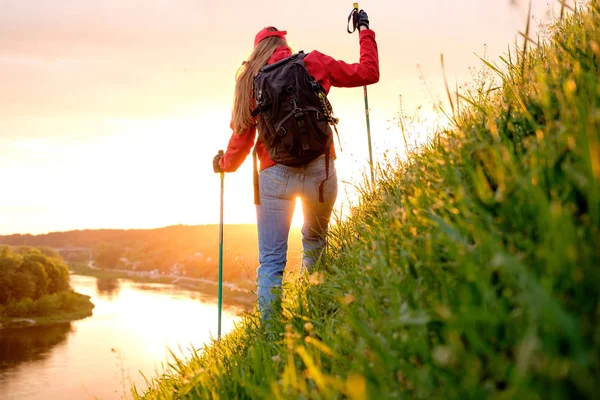 Mujer joven caminando sobre colinas con mochila y bastones de senderismo — Foto de Stock