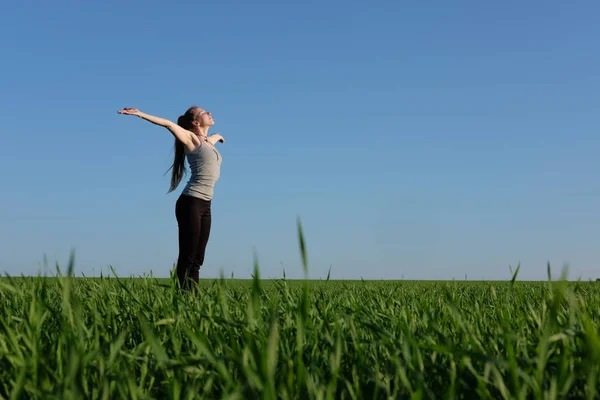 Ragazza che si estende in campo verde con sfondo cielo blu — Foto Stock