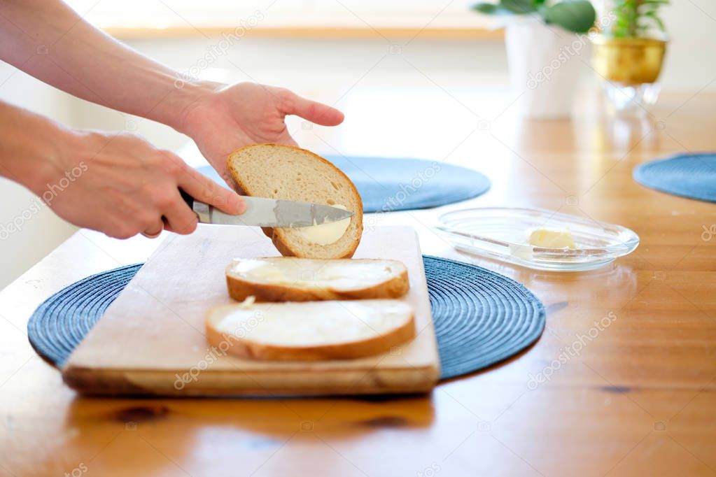 woman making breakfast, spreading butter on bread