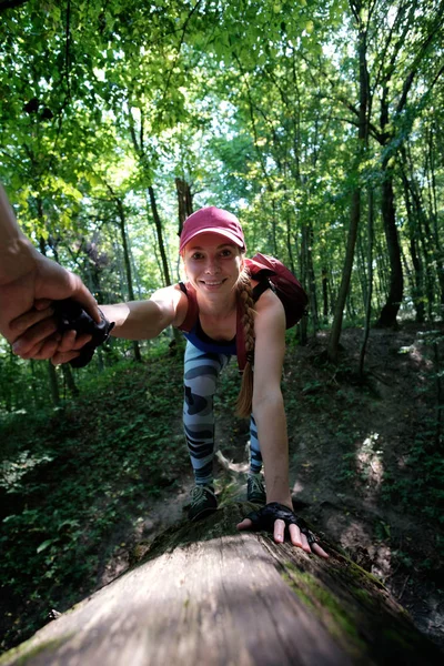 Fille randonnée dans la forêt, escalade jusqu'à la bûche. Homme tenant la main — Photo