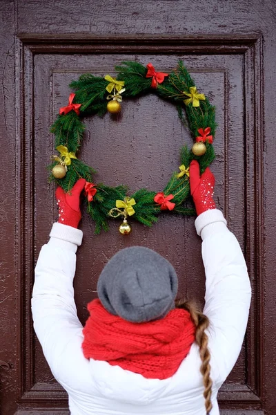 Kız kırmızı eşarp ve Noel çelenk t üzerinde asılı beyaz ceket