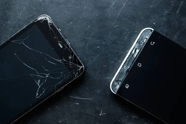 broken smartphone on black background