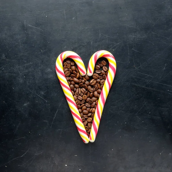 Caramelos de caña en forma de corazón con granos de café vista plana en negro — Foto de Stock
