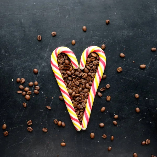 Caramelos de caña en forma de corazón con granos de café vista plana en negro — Foto de Stock